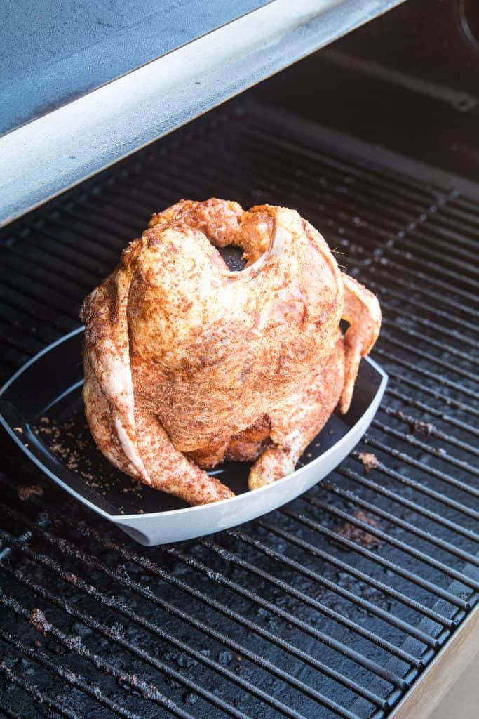 Whole Chicken on Beer Can holder on the smoker that's seasoned and raw.