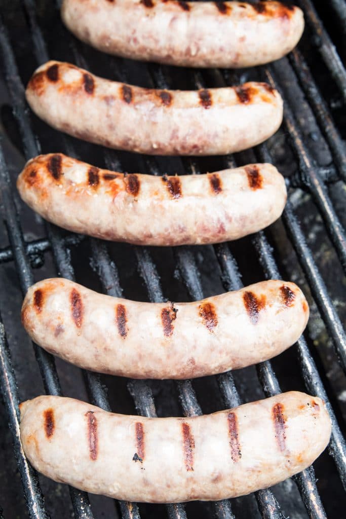 Brats on grill grates with sear marks.