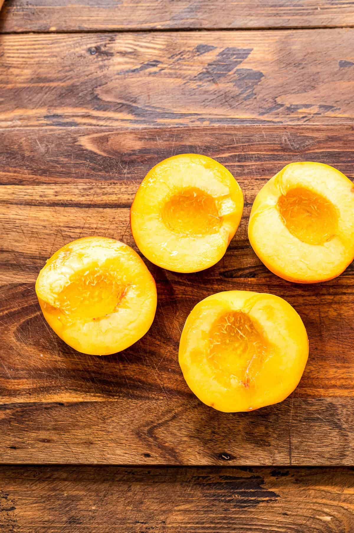 Peaches cut in half laying on wooden background.