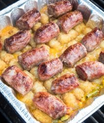 Foil pan with brat tater tot casserole on it on the grill.