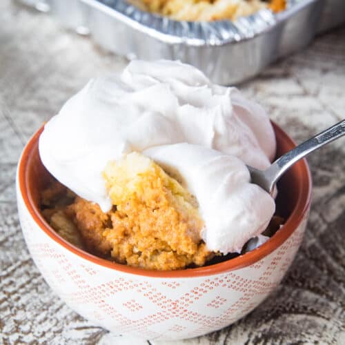 Smoked Pumpkin Dump Cake in bowl topped with cool whip