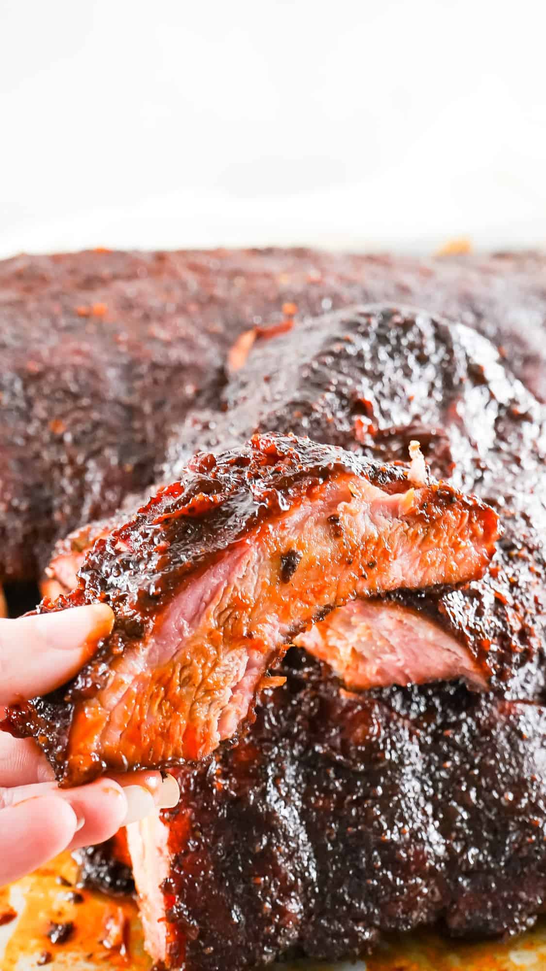 Hand holding a piece of smoked ribs