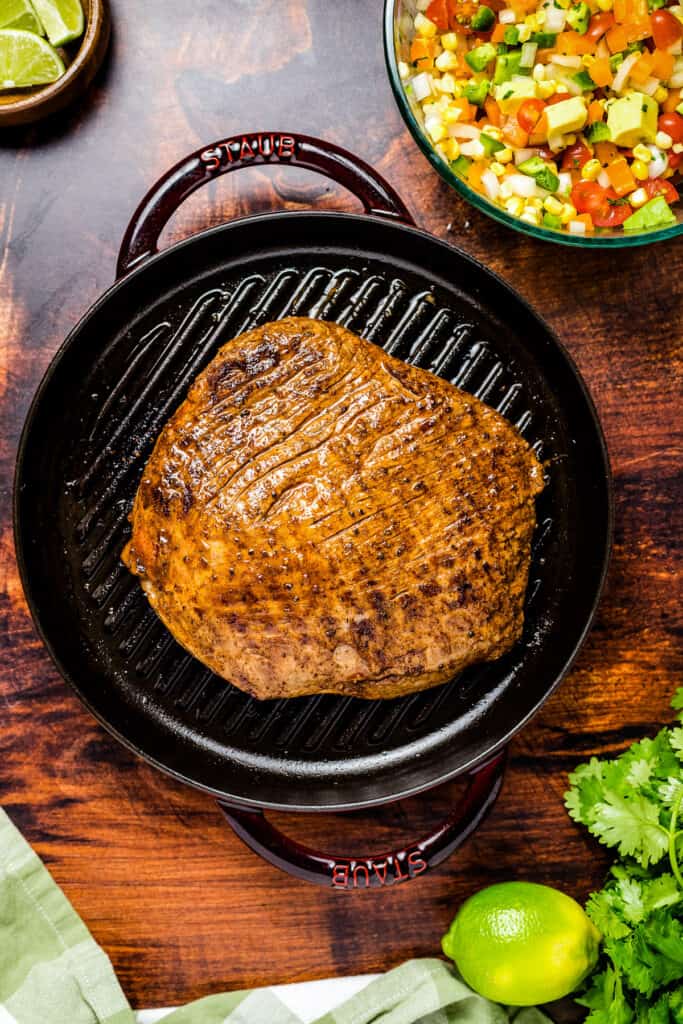 Overhead image of grilled flank steak in cast iron pan