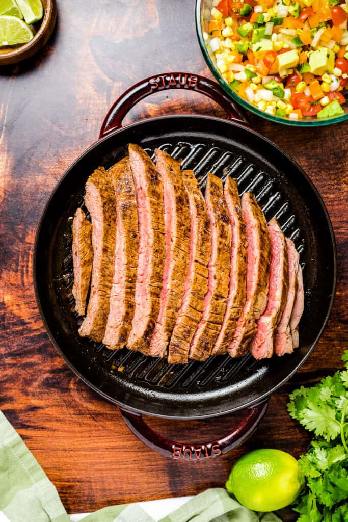 Overhead image of sliced flank steak in cast iron pan