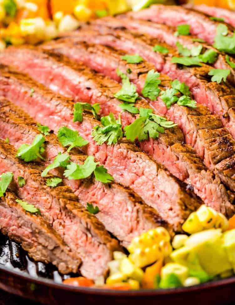Sliced Grilled Flank Steak topped with chopped parsley and corn salsa