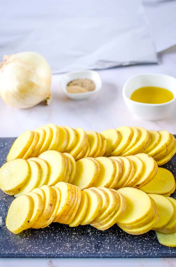 Thinly sliced potatoes on cutting board
