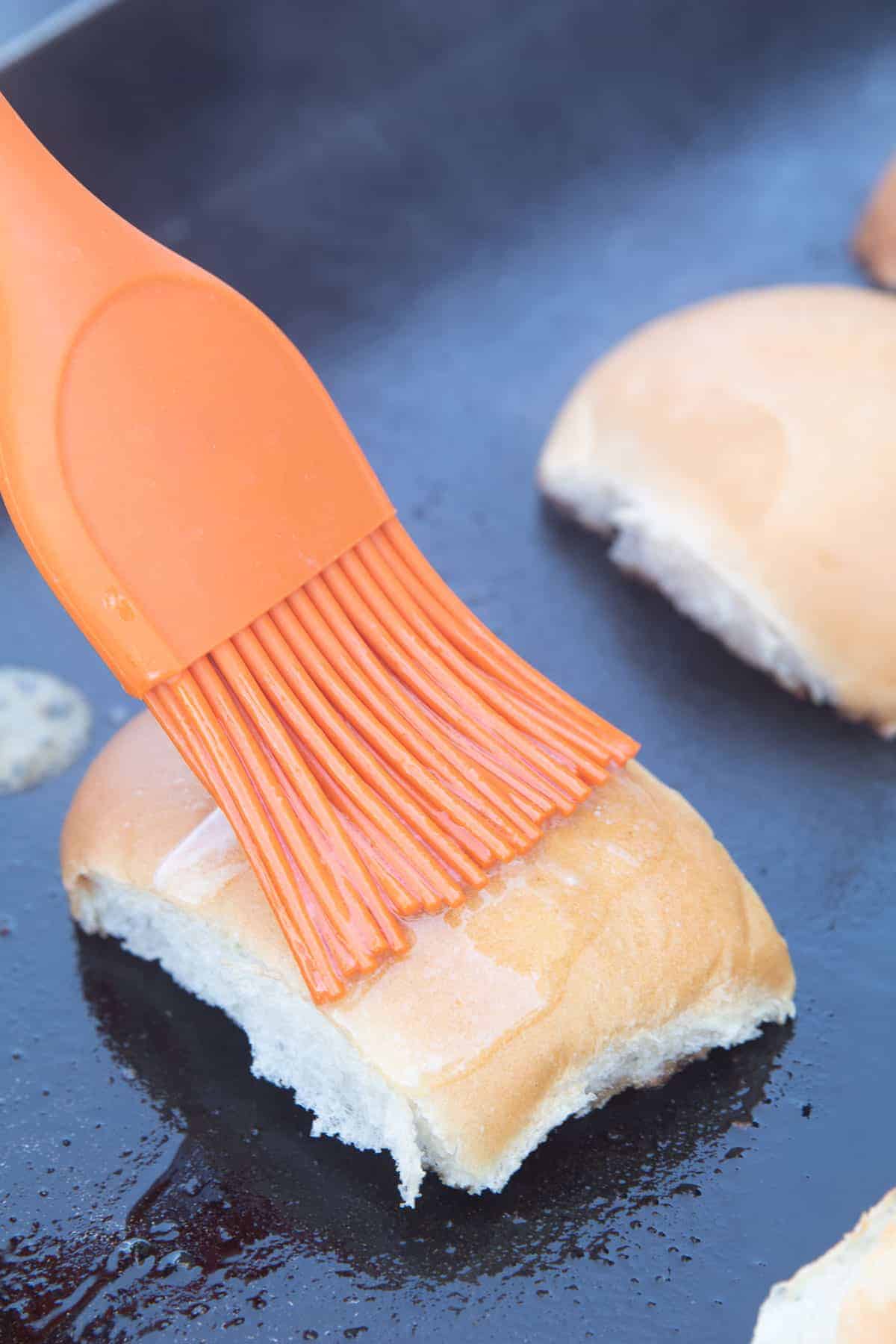 Pastry brush putting melted butter on top of buns