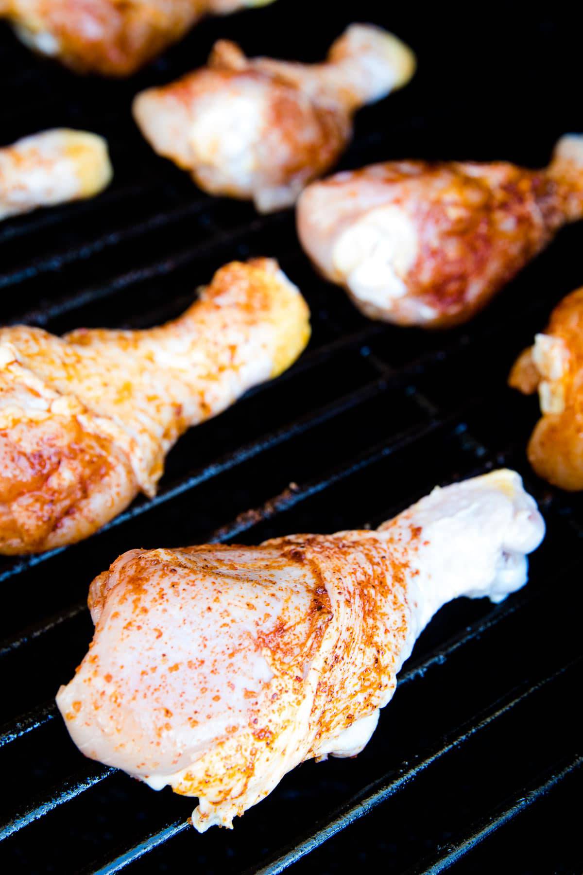 Seasoned chicken legs on smoker grates