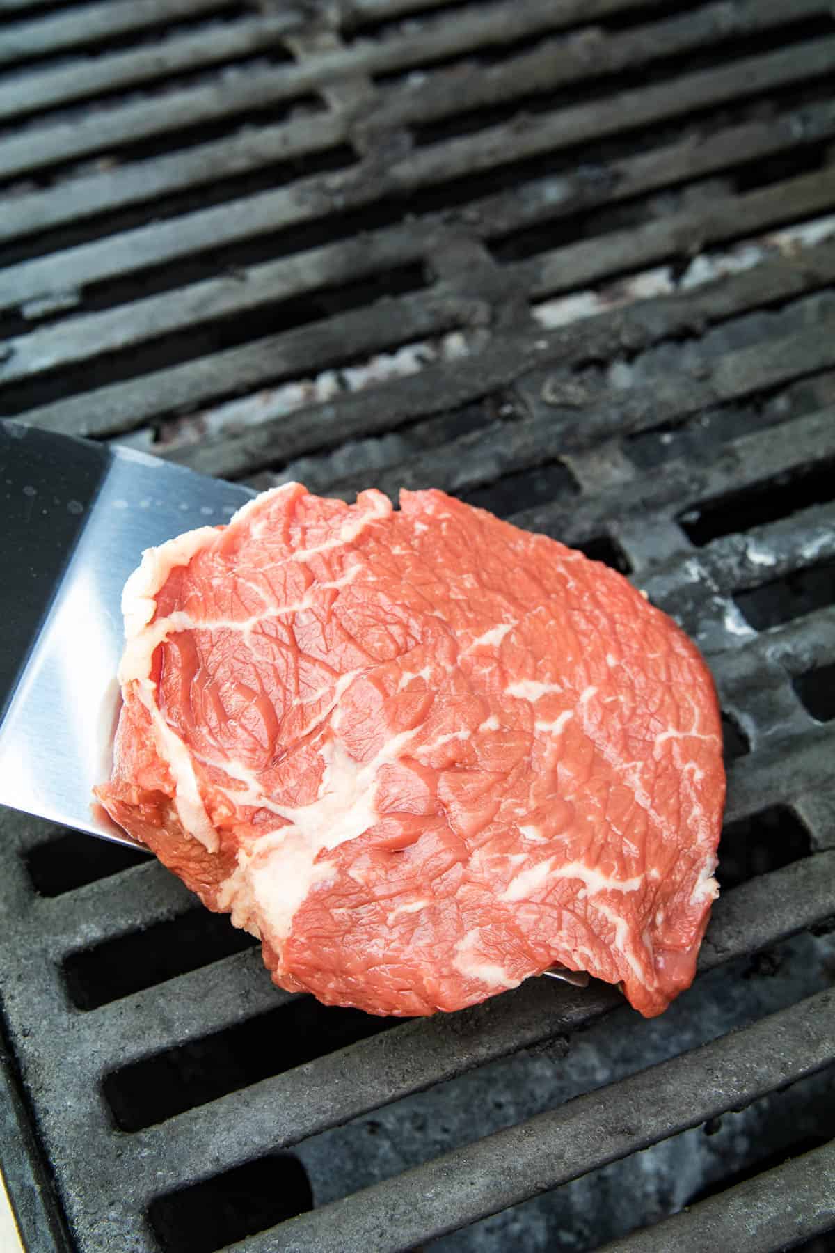 Spatula placing ribeye on grill