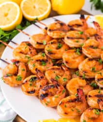 White plate with spicy grilled shrimp skewers on it