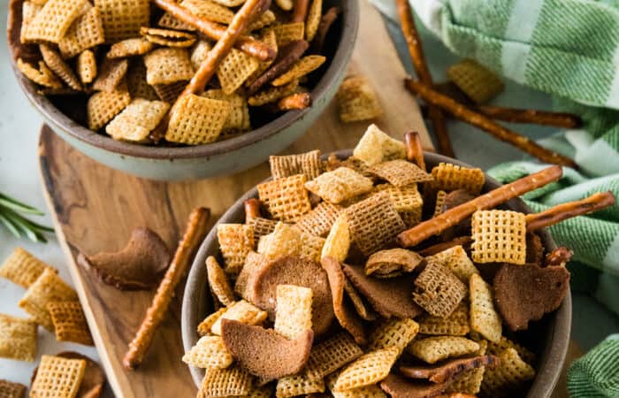 Bowls of chex mix on wood cutting board