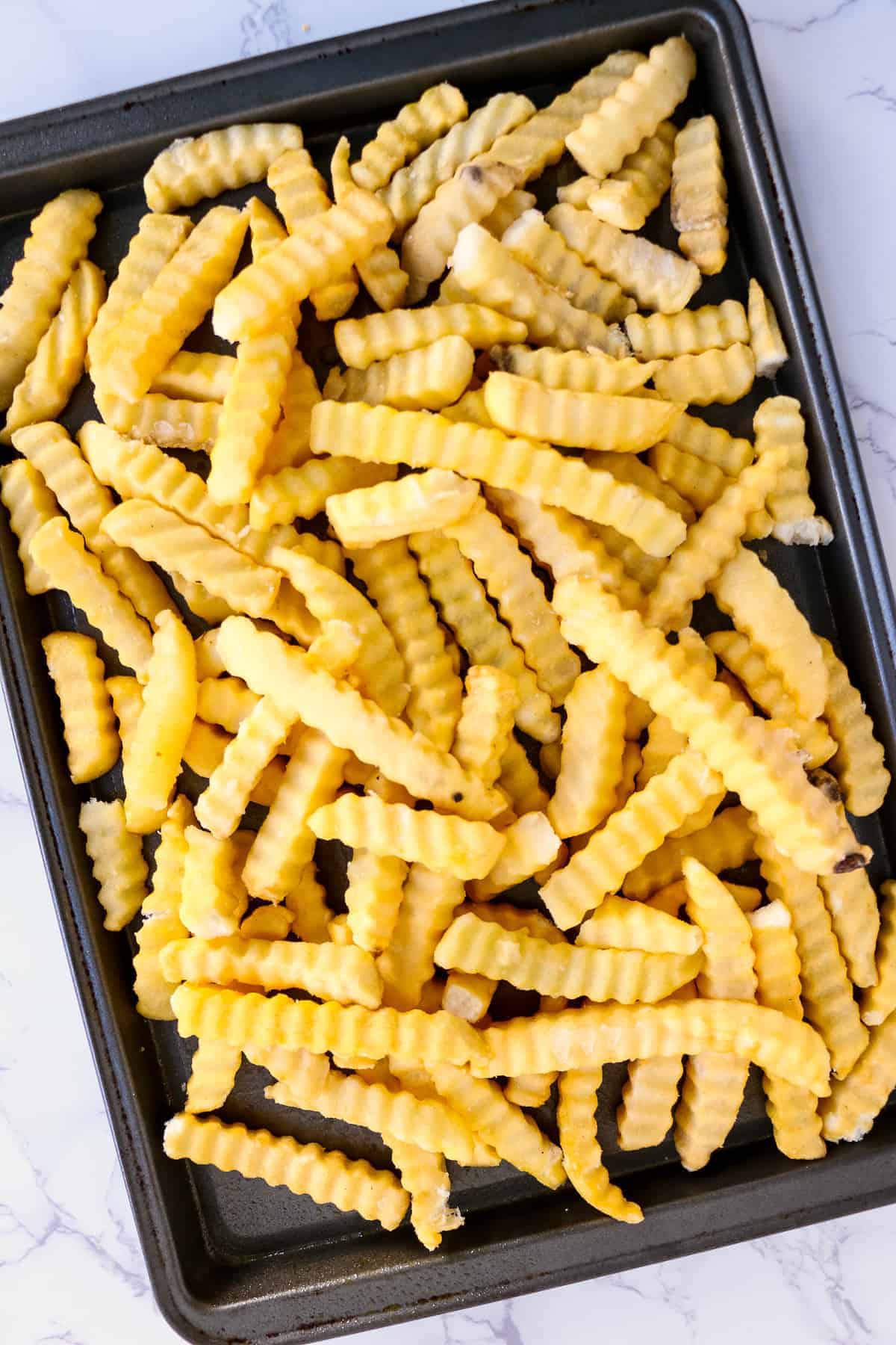 Sheet pan with frozen french fries on it