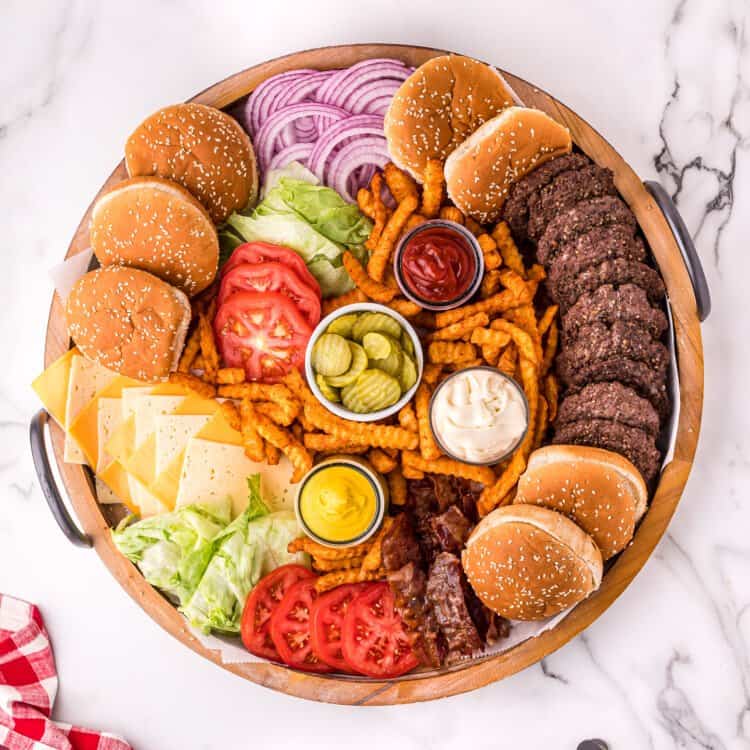 Overhead image of round wood platter with burgers and toppings