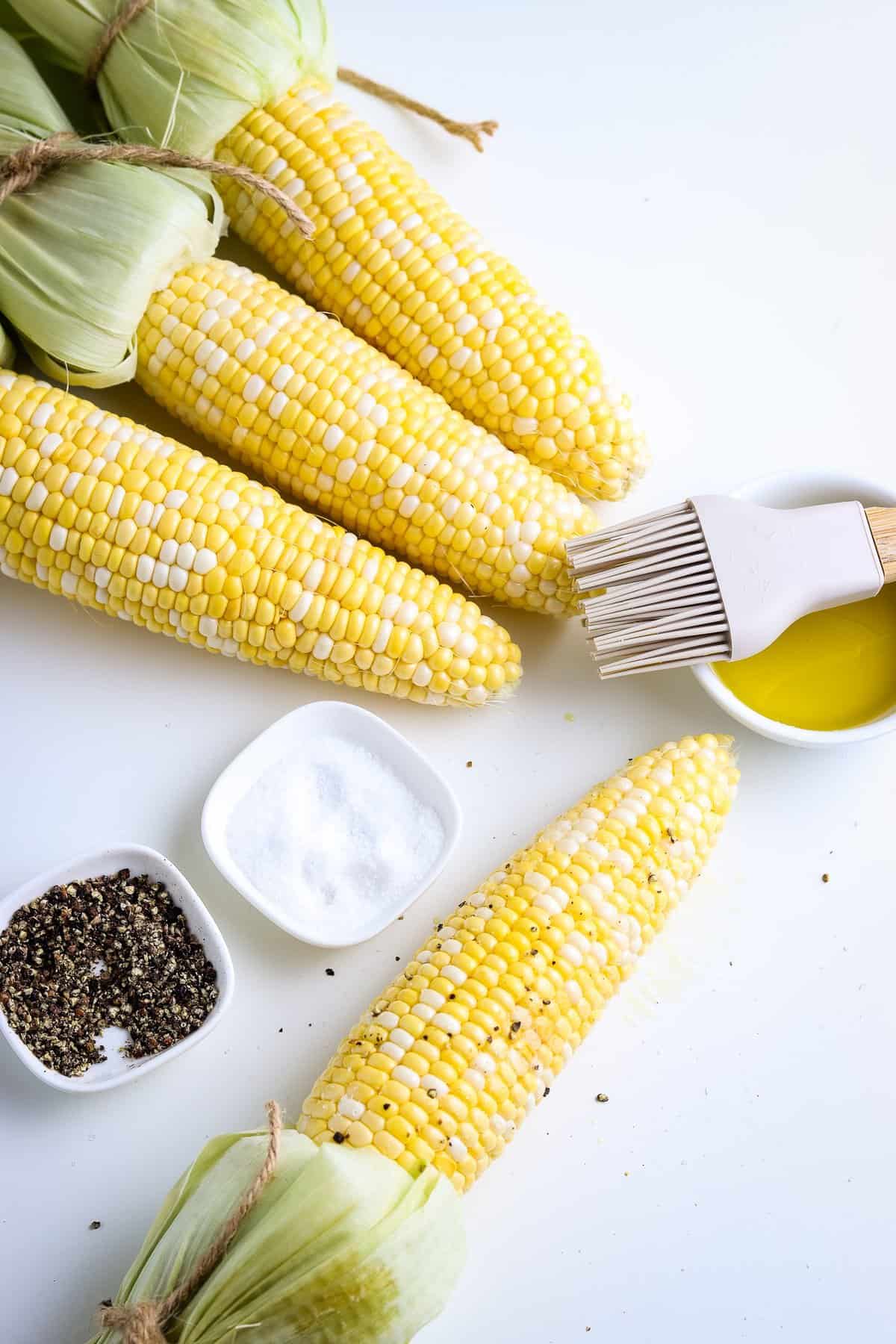 Husked corn on the cob with salt pepper and oil