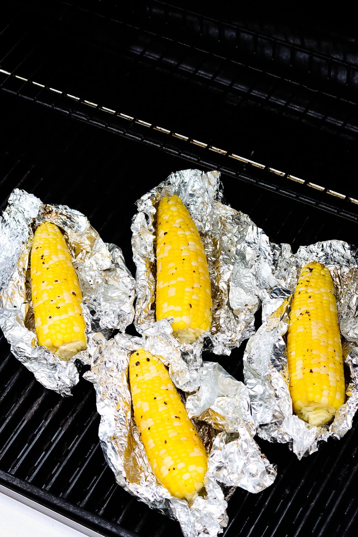 Unwrapped grilled corn on the cob in foil pieces