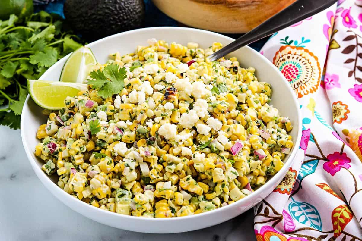 White bowl with Mexican Street Corn salad and a spoon in it