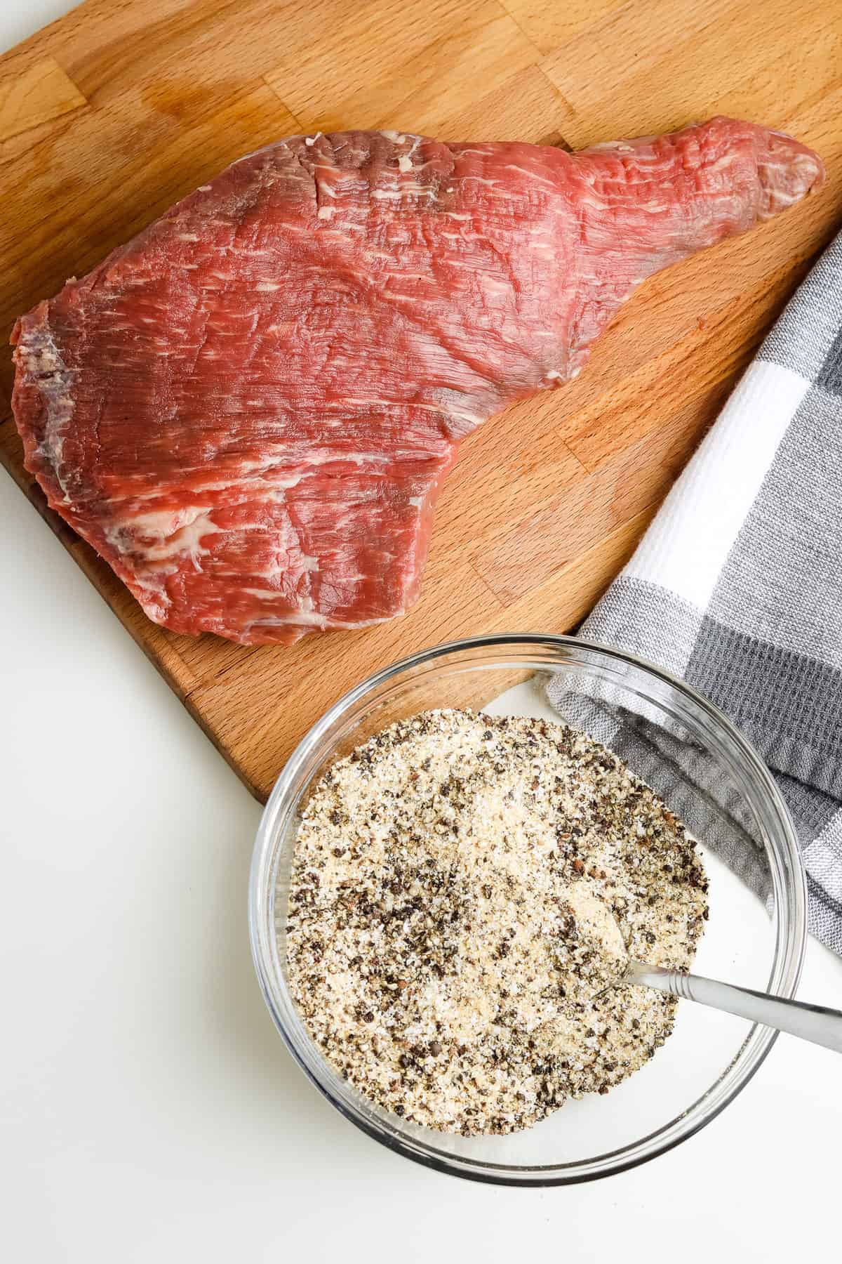 Tri tip on cutting board with seasonings mixed in bowl