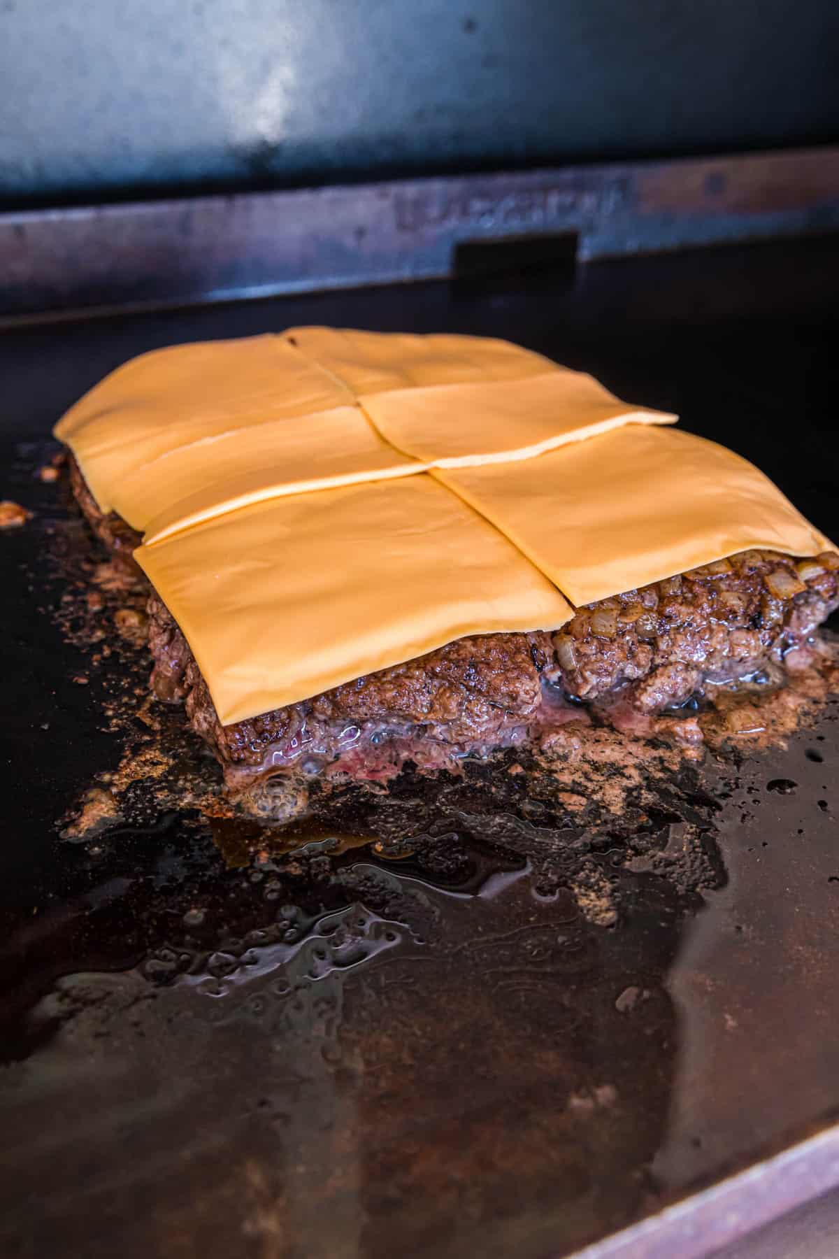 Topping Ground Beef with American Cheese for Blackstone Bacon Cheeseburger Sliders Recipe