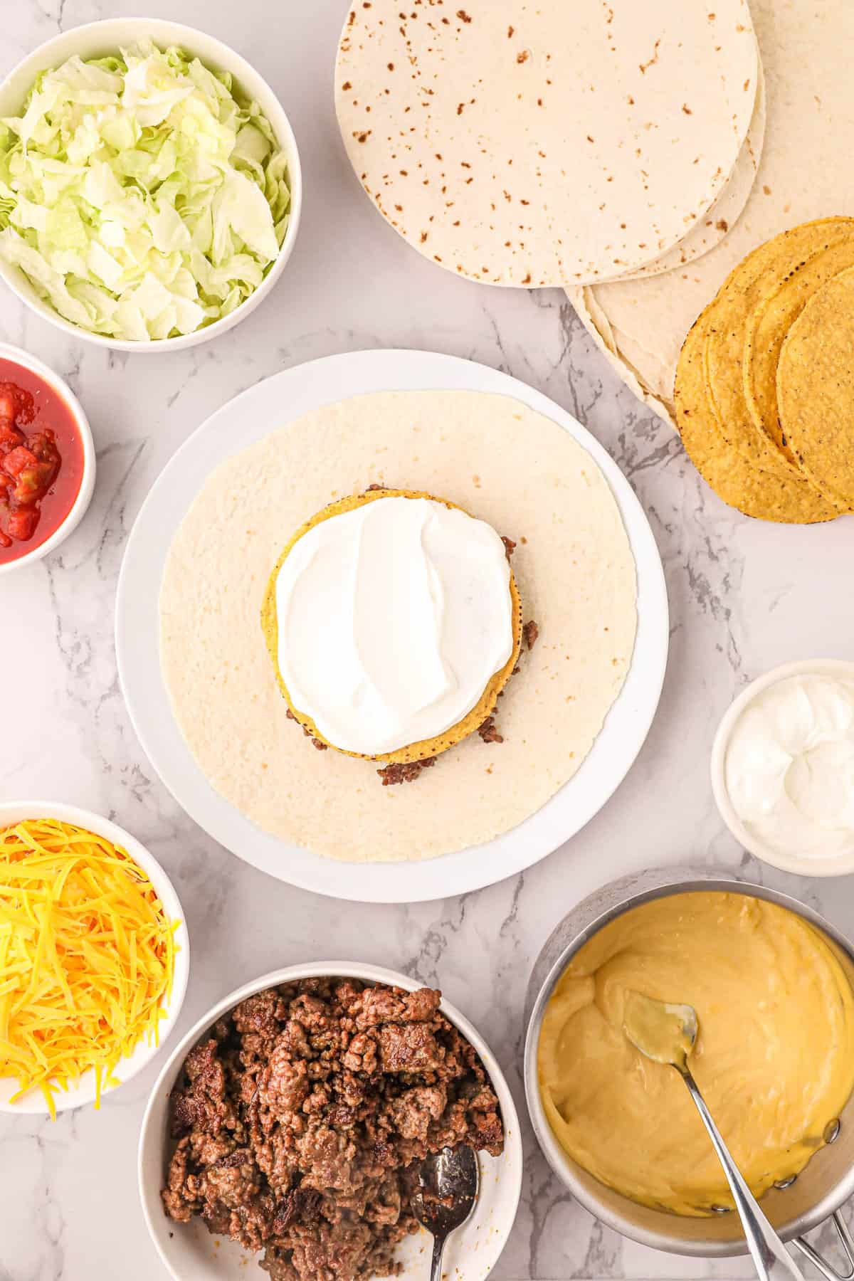 Spreading Sour Cream on Tostada Shell for Blackstone Crunchwrap Recipe