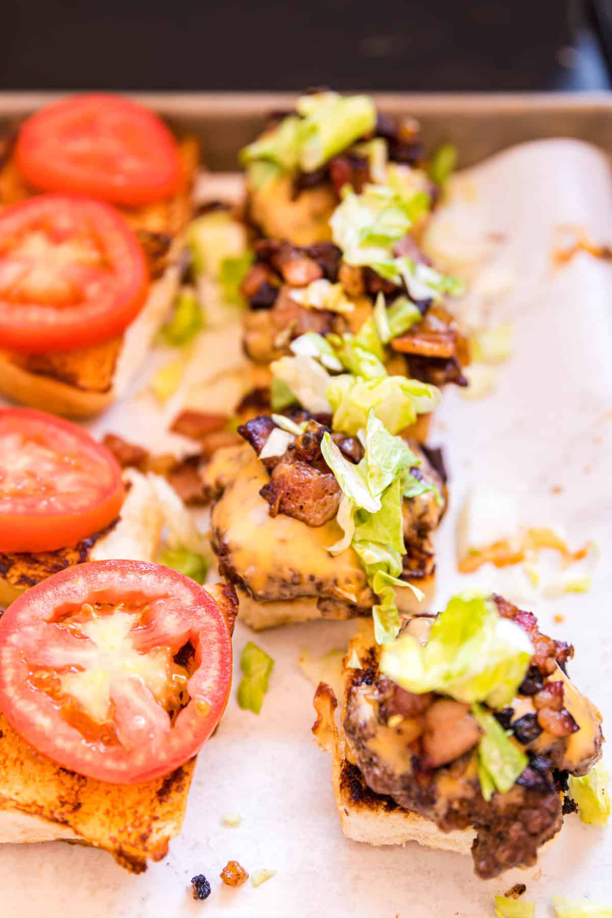 Loading Blackstone Smash Burger Sliders with Bacon, Lettuce, and Tomato.