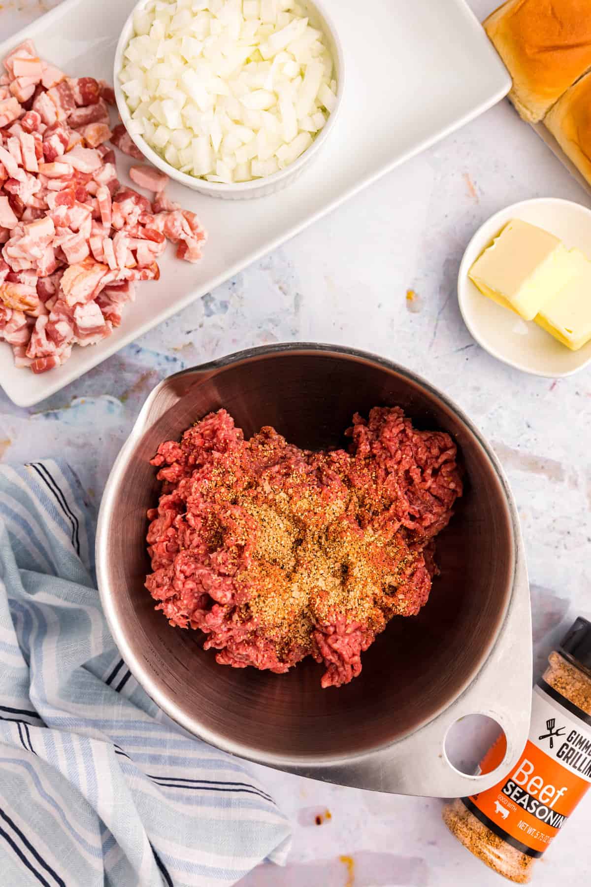 Combining ground beef and Gimme Some Grilling beef seasoning in bowl for Blackstone Smash Burger Sliders