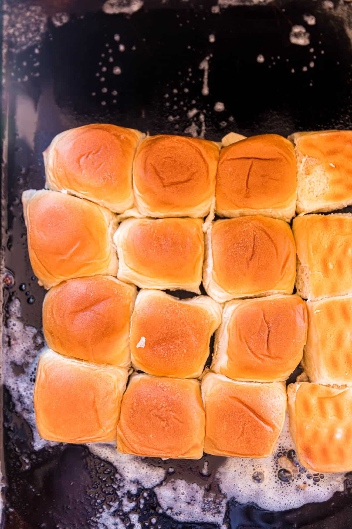 Slicing hawaiian rolls and placing face down on butter griddle for Blackstone Smash Burger Sliders