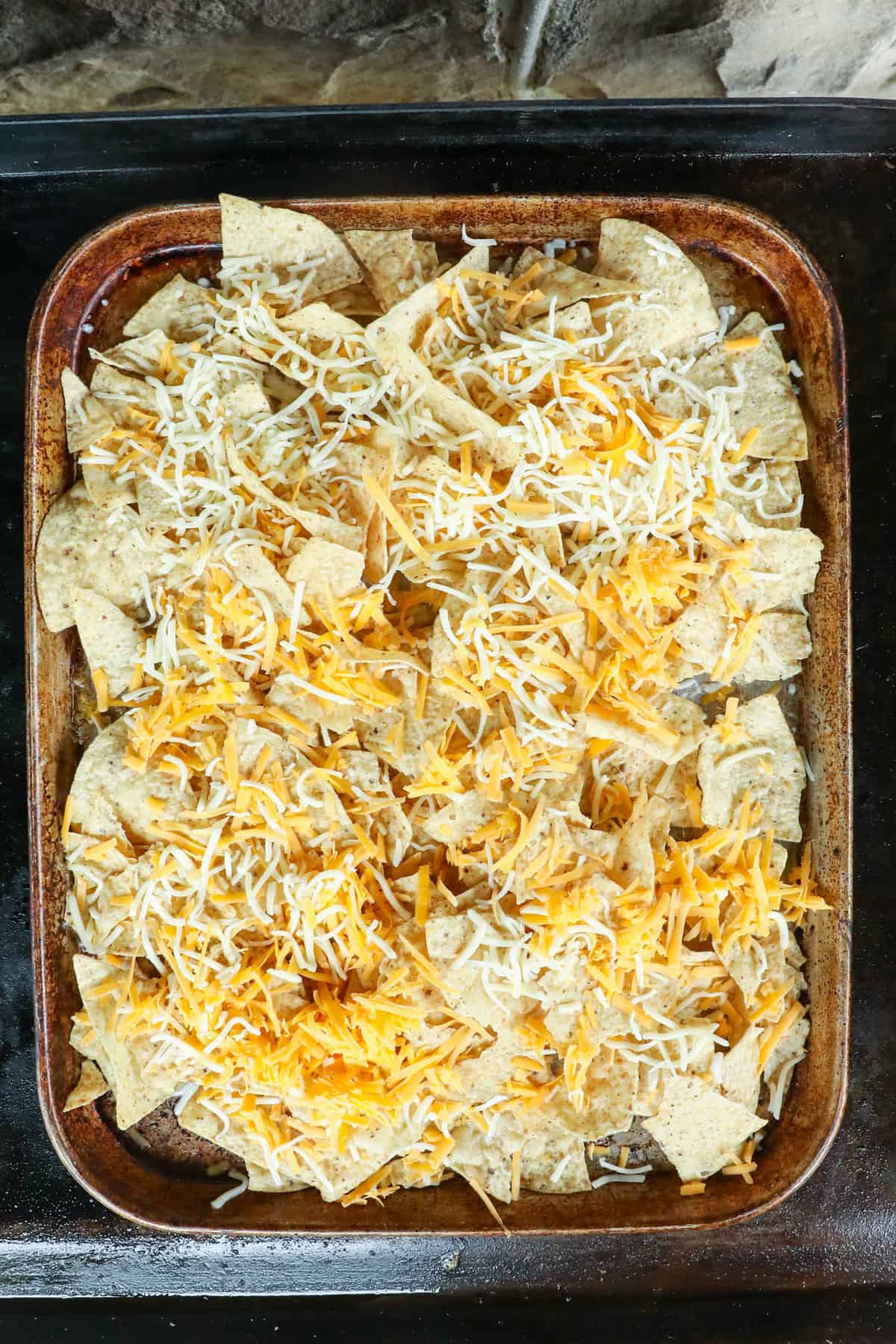 Topping tortilla chips with cheeses for Blackstone Nachos