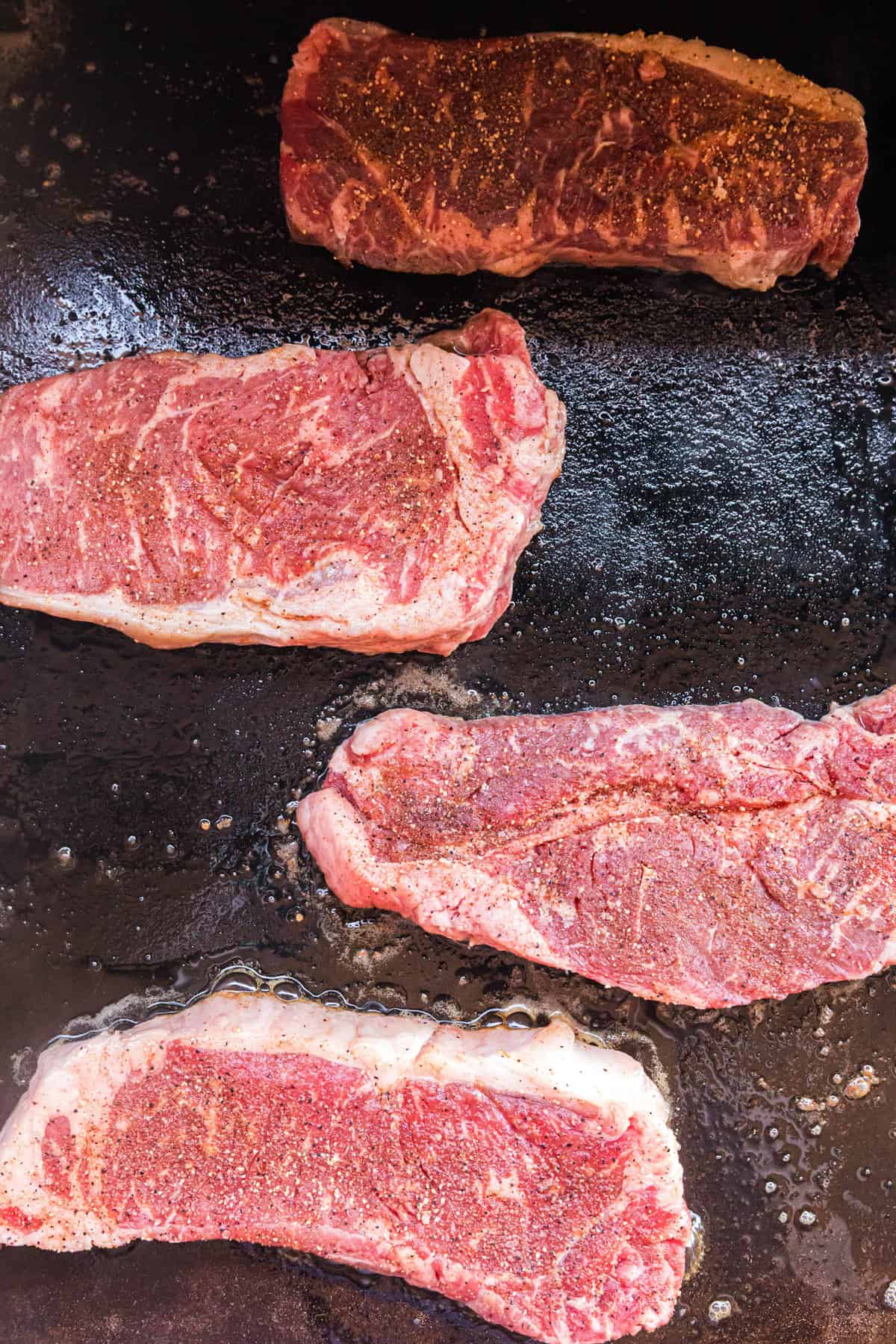 Steaks on buttered Blackstone griddle