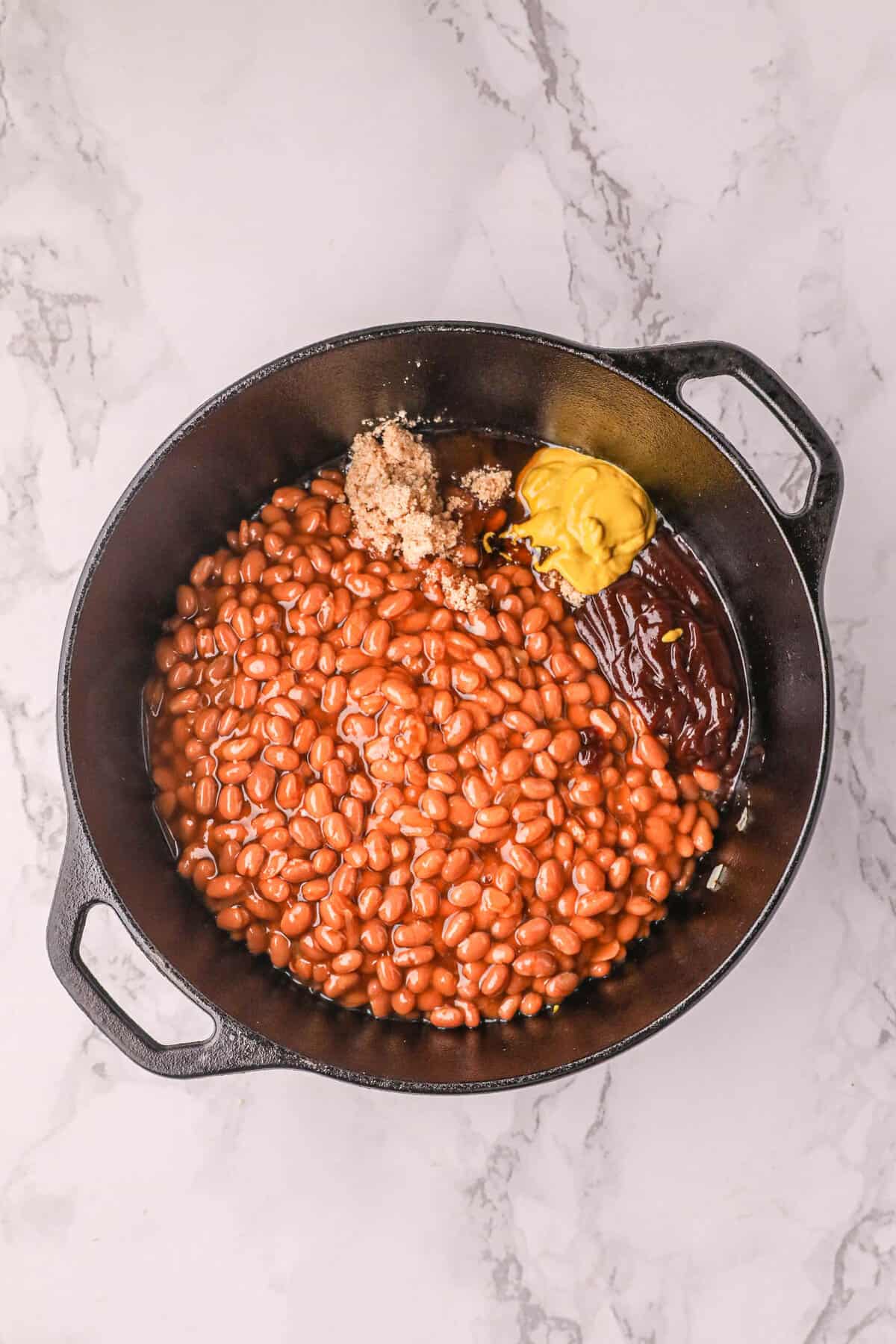 Adding remaining ingredients to cooked bacon for Smoked BBQ Beans in the dutch oven 