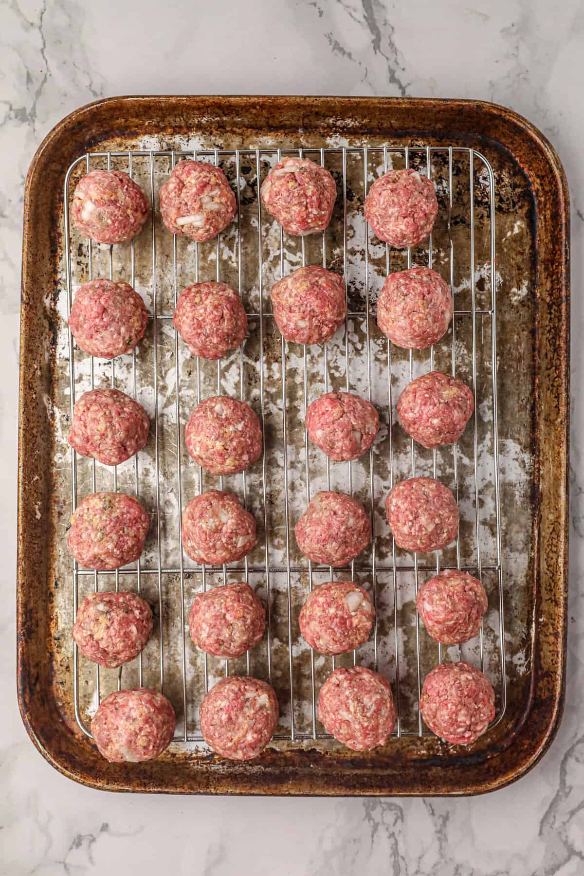 Forming meatballs around string cheese chunks and arranging on wire rack for Smoked Stuffed Meatballs recipe