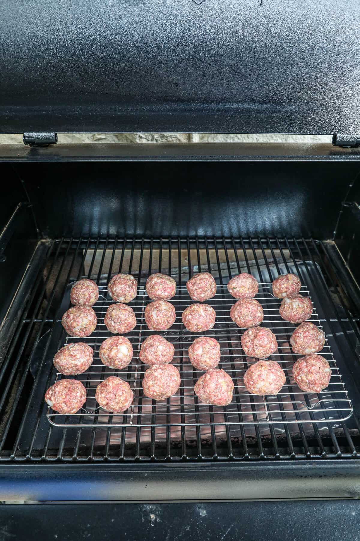 Placing meatballs on wirerack in smoker for Smoked Stuffed Meatballs
