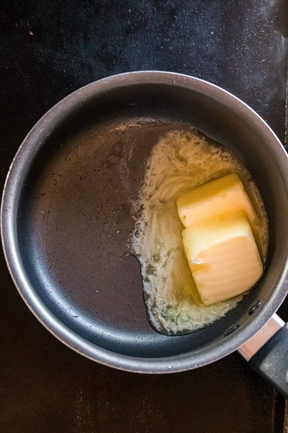 Melting salted butter in saucepan over the Blackstone griddle for Blackstone Popcorn