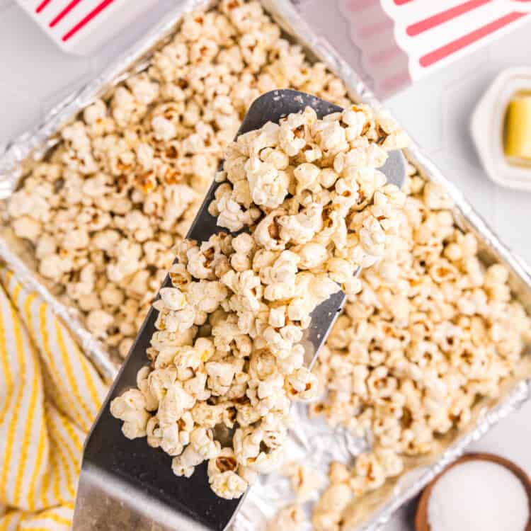 Scooping popped popcorn from tinfoil-lined baking sheets for Blackstone Popcorn recipe