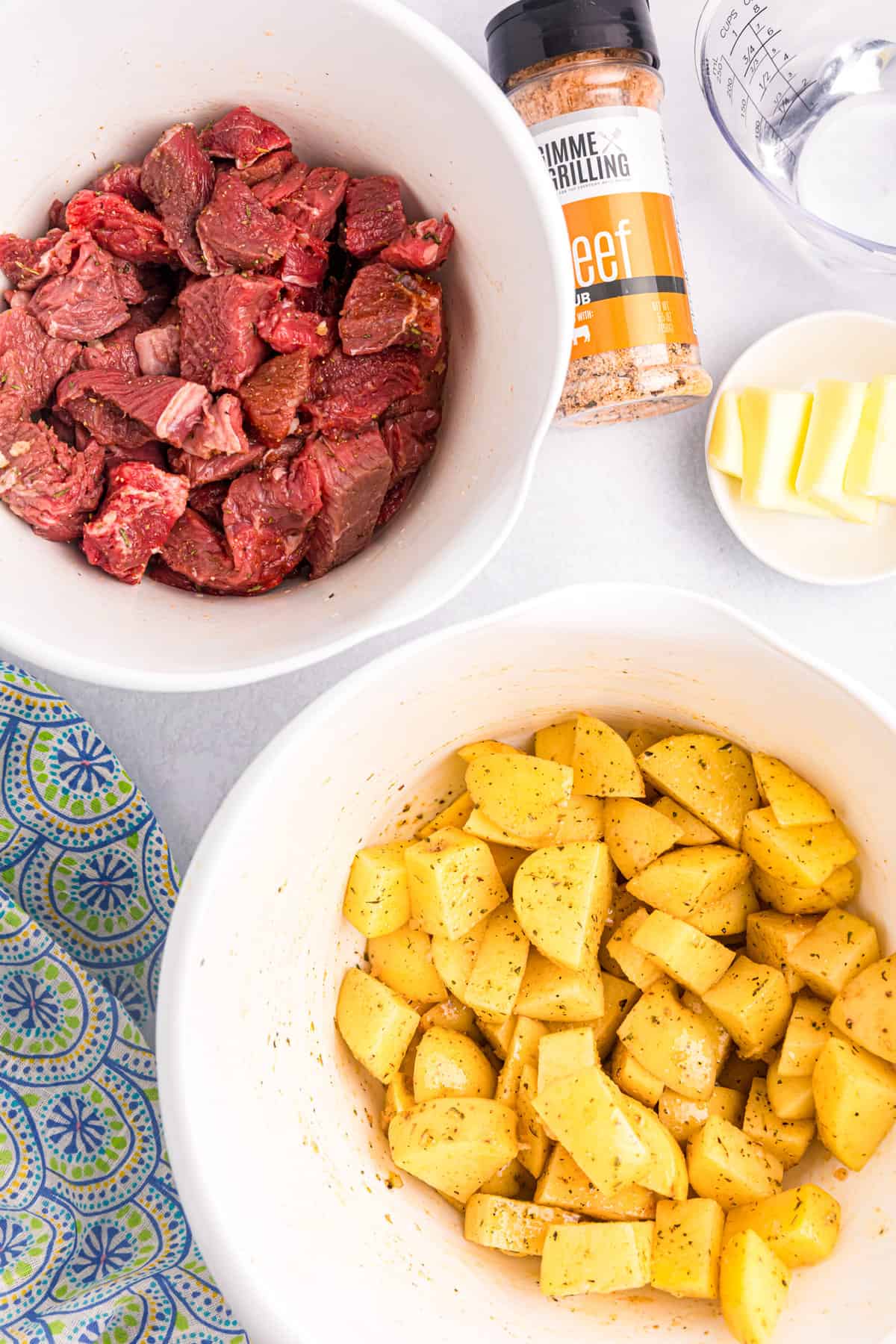 Seasoned and tossed steak and potatoes cubed in mixing bowls for Blackstone Steak and Potatoes recipe