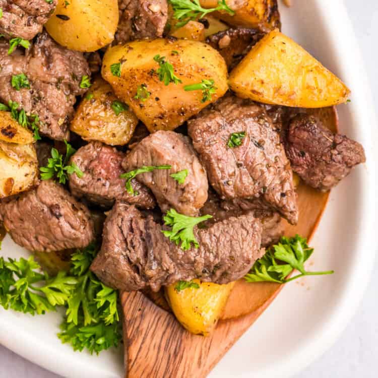 Steak and Potatoes on the Blackstone in a serving bowl with a wooden spoon