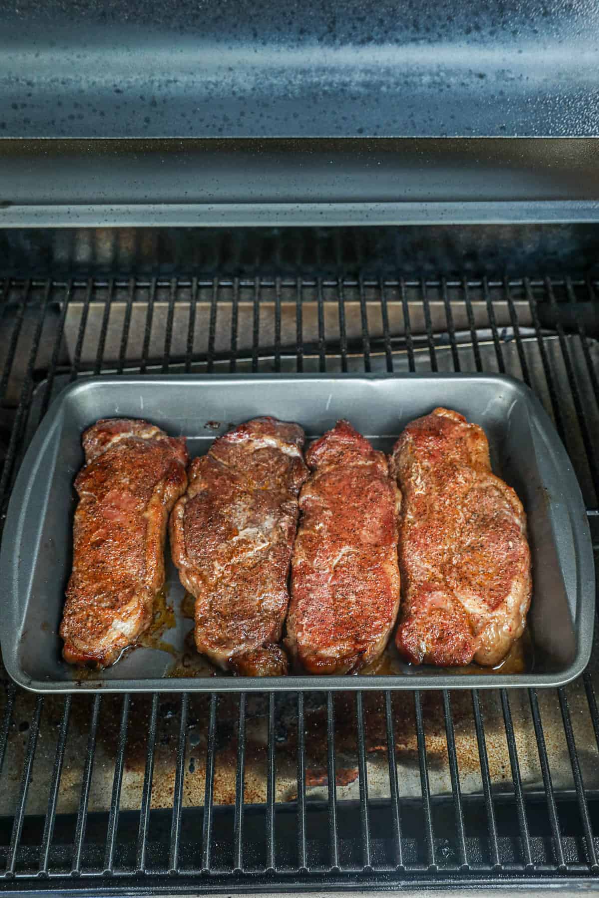 Putting smoked steaks in cooking pan back on smoker