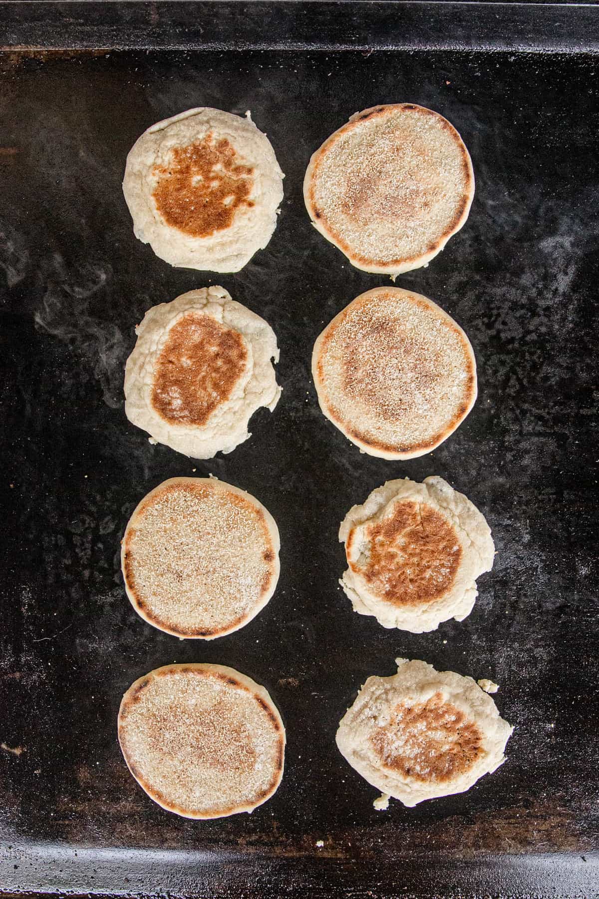 English muffins face down on Blackstone griddle for Blackstone Breakfast Sandwiches