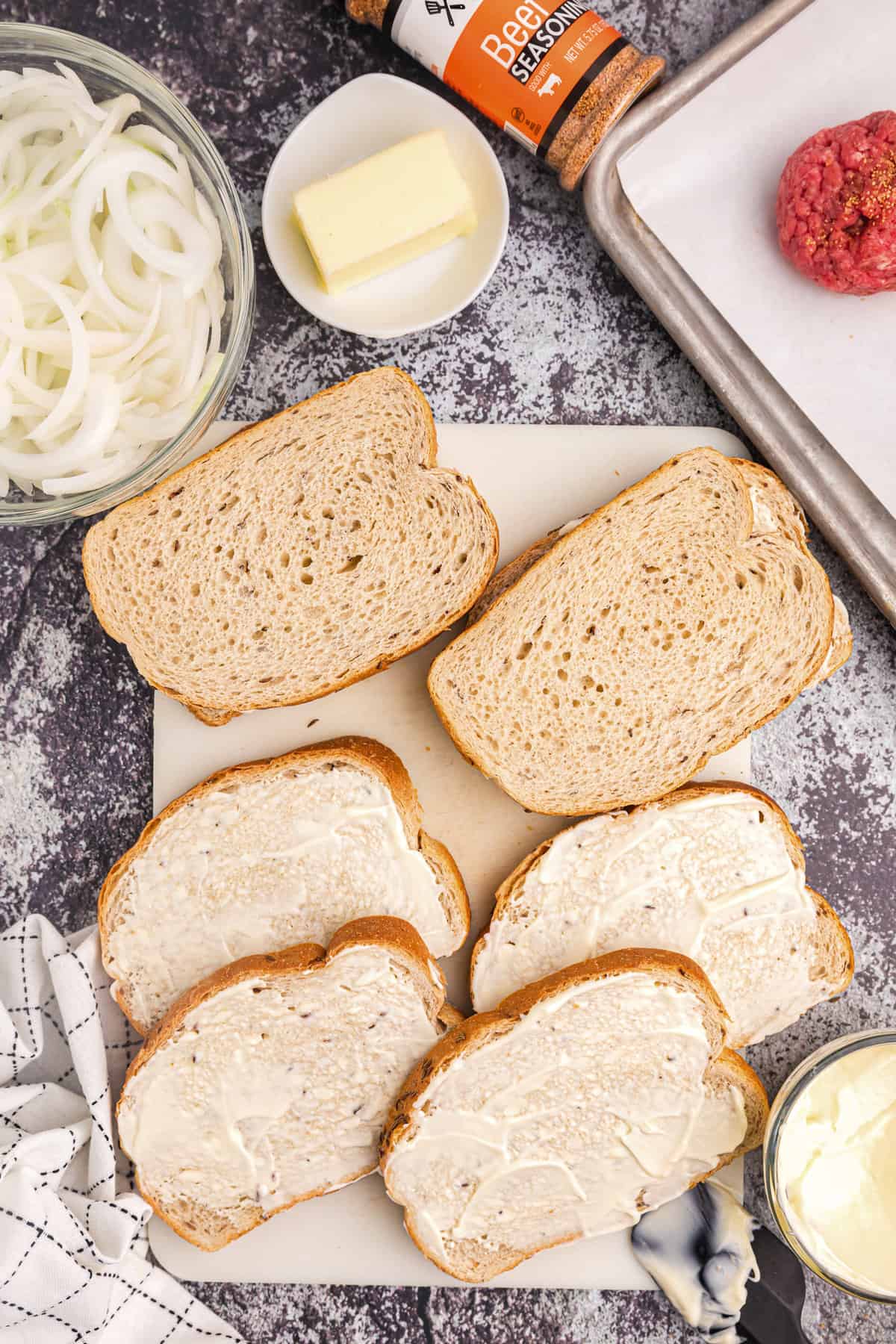 Spreading mayonaise on one side of bread slices for Blackstone Patty Melt recipe