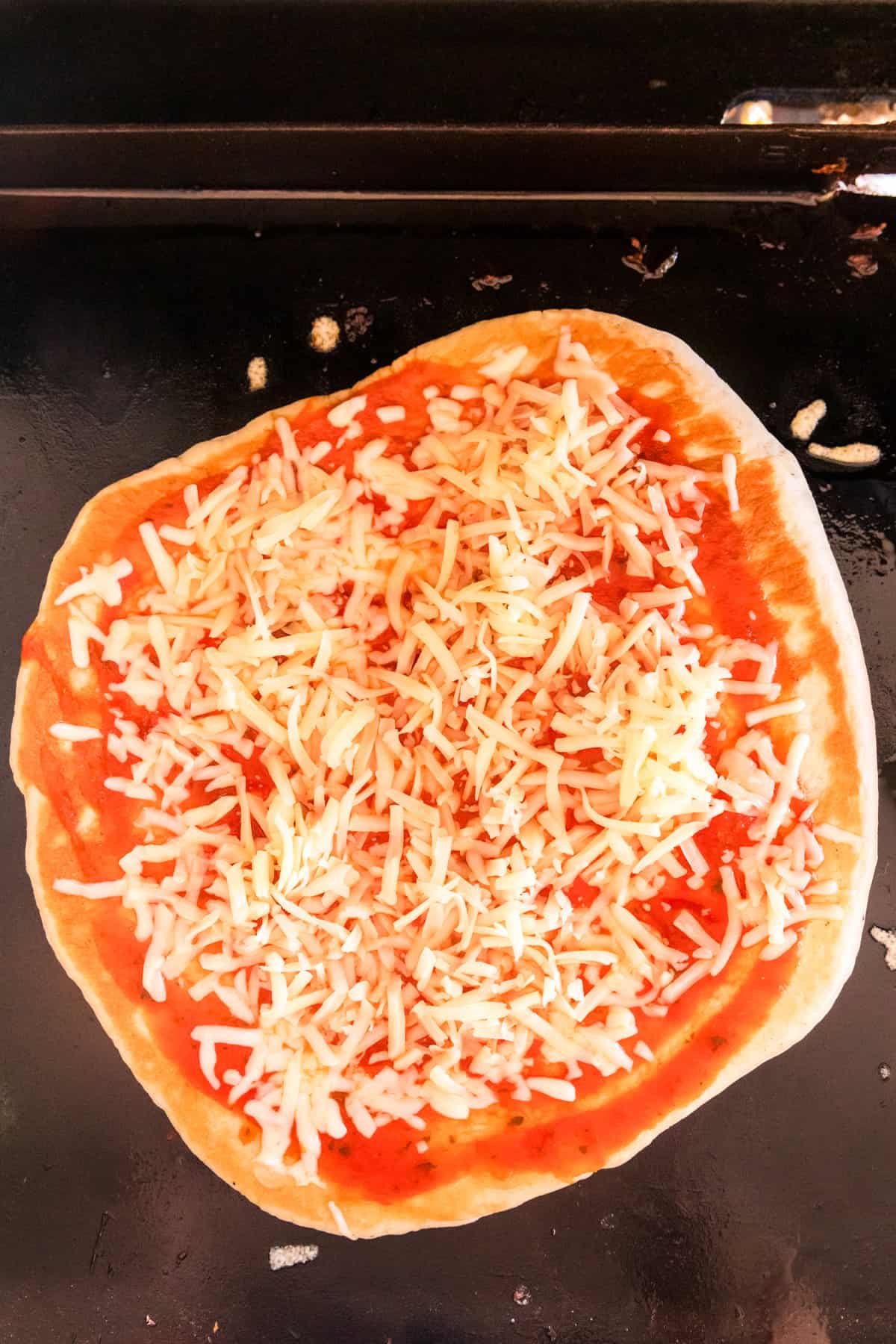 Adding pizza sauce and cheese to Blackstone Pizza crust