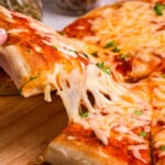 Closeup Square Image of Blackstone Pizza cut into slices on wooden cutting board