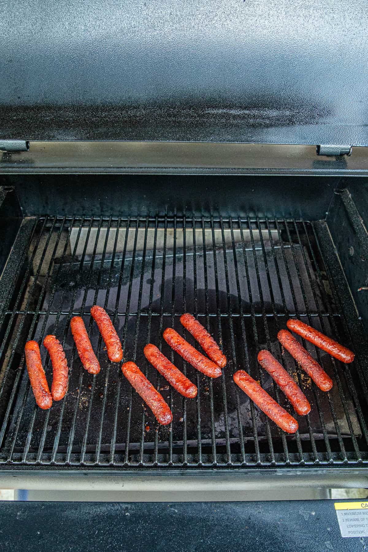 Flipping hot dogs on Traeger grill for Smoked Hot Dogs recipe