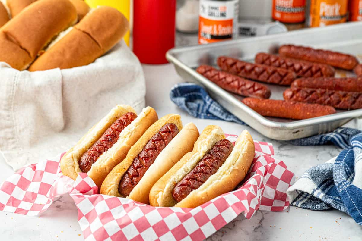 Smoked Hot Dogs on the Traeger in buns arranged in paper lined serving tray