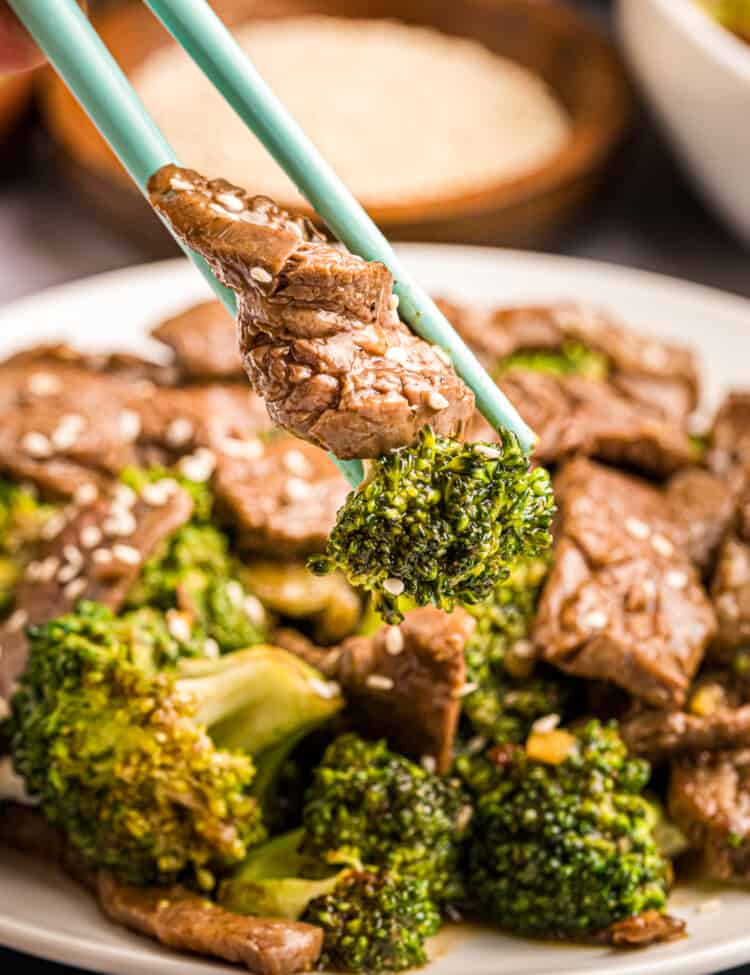 Blackstone Beef & Broccoli in shallow bowl using chopsticks to eat with