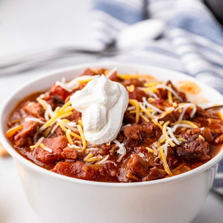 Smoked Brisket Chili in bowl with sour cream and shredded cheese toppings