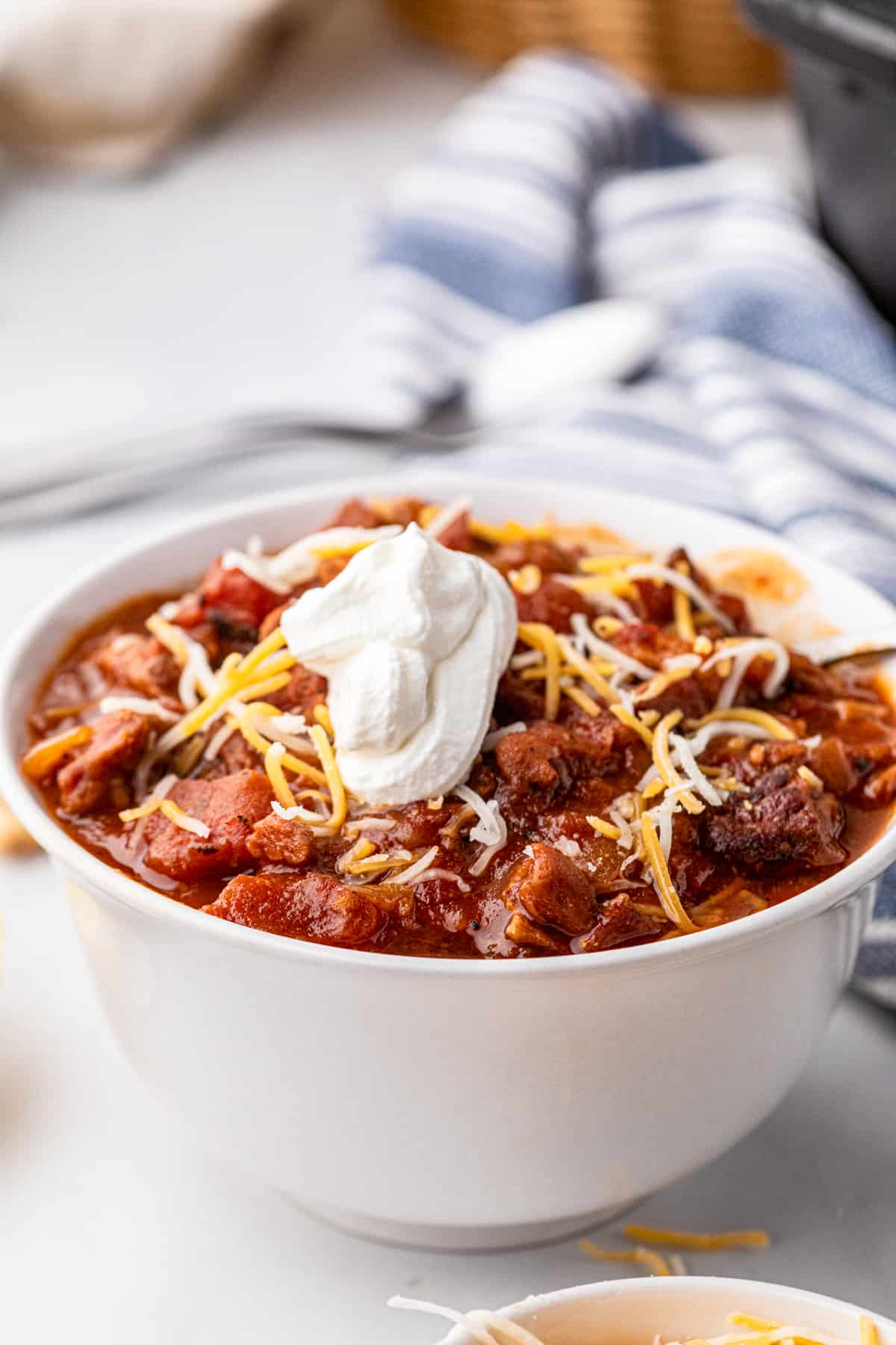 Smoked Brisket Chili in bowl with sour cream and shredded cheese toppings