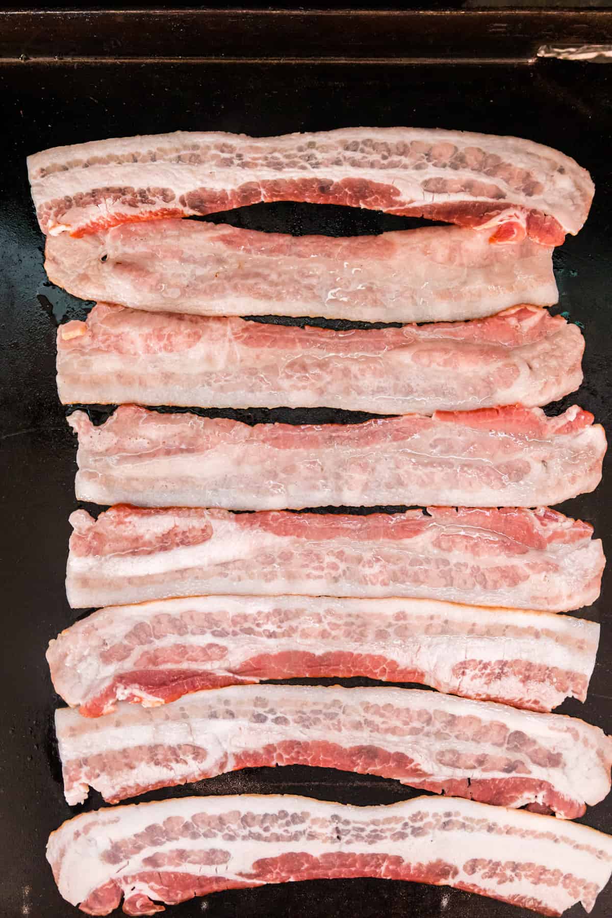 Arranging bacon silces on Blackstone griddle for  Breakfast Sliders