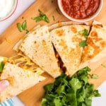 Blackstone Chicken Quesadilla cut into pieces on wood cutting board with salsa