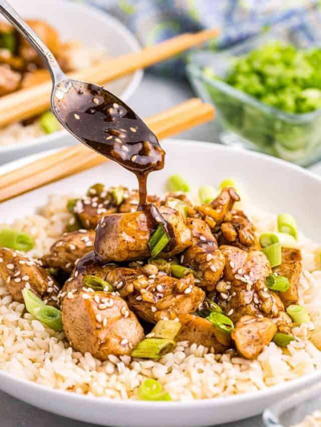 Blackstone Teriyaki Chicken over a bed of rice with spoong drizzling soy sauce and seasame seeds