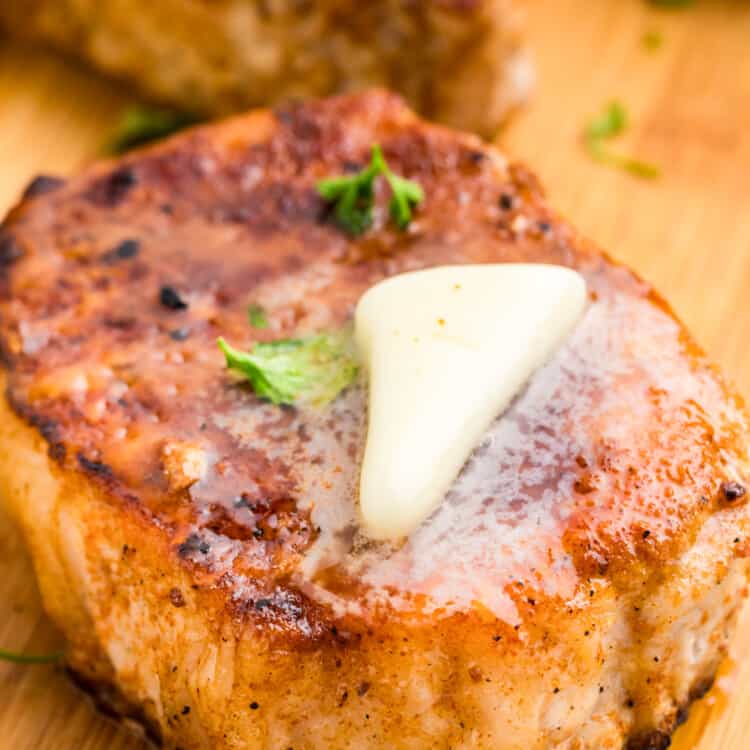 Allowing pork chops to rest on cutting board with butter melts on top of them for Blackstone Pork Chops