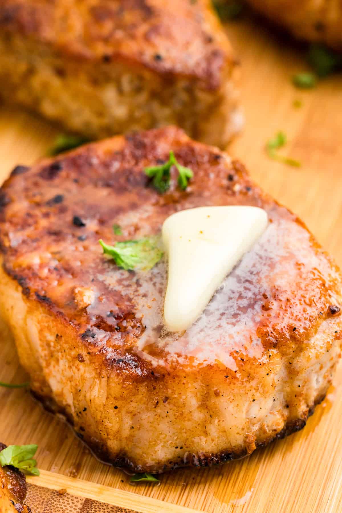 Allowing pork chops to rest on cutting board with butter melts on top of them for Blackstone Pork Chops